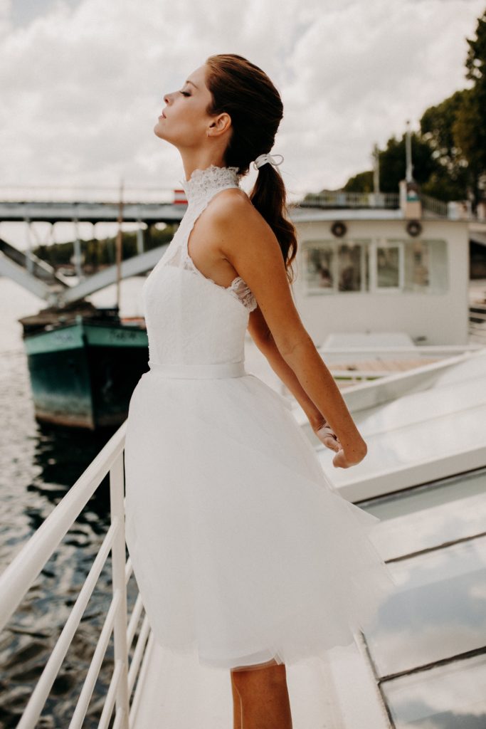 femme dans une robe de mariée courte en dentelle devant la Seine à Paris