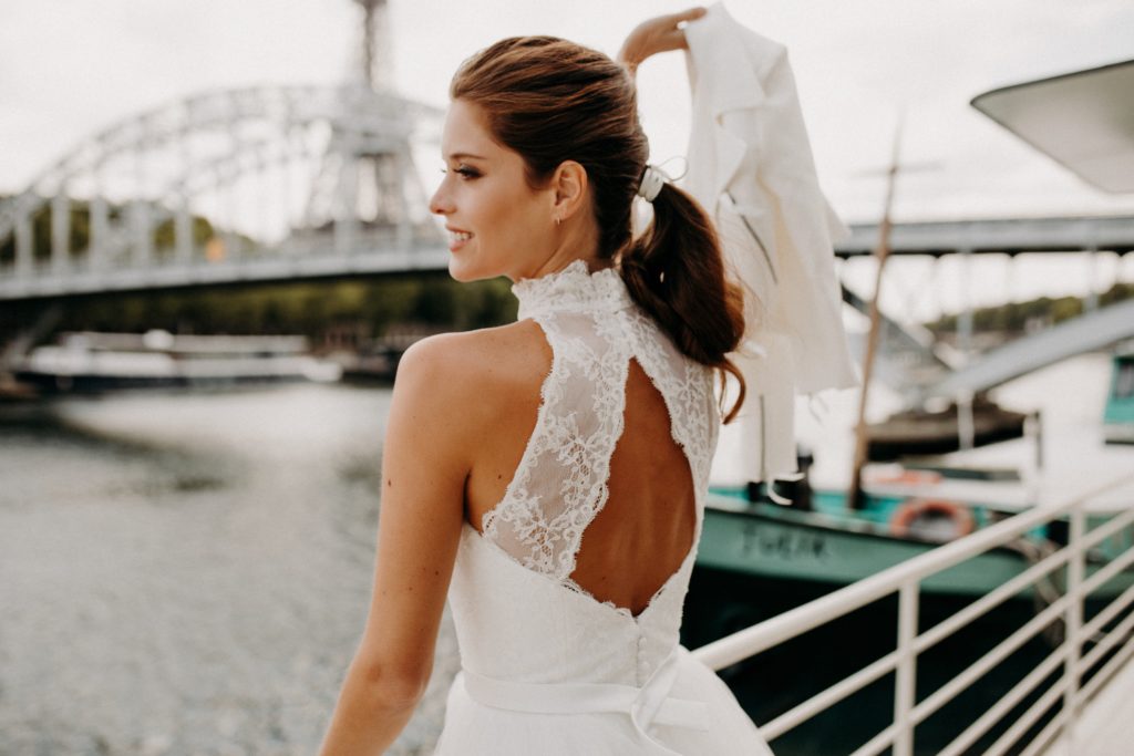 femme dans une robe de mariée courte en dentelle devant la Seine à Paris