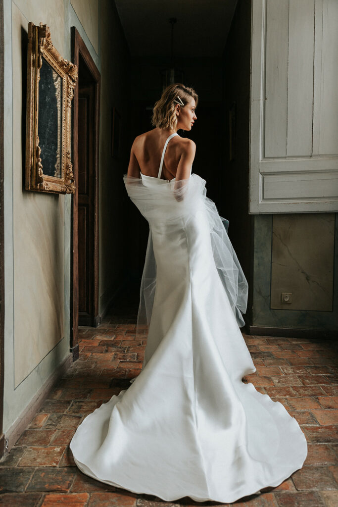 femme avec une robe de mariée glamour et épurée en mikado dans un château