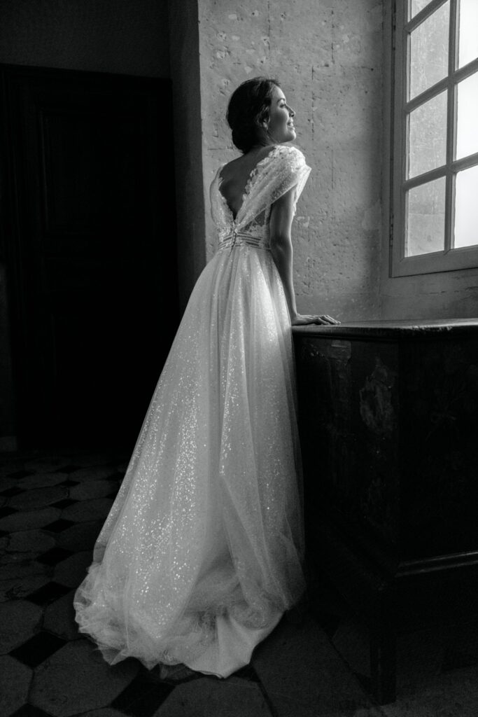 femme dans une robe de mariée brillante dans un château