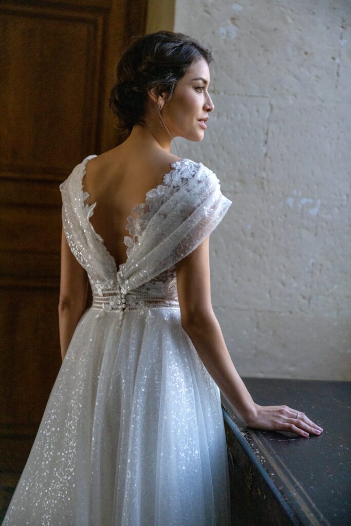 femme dans une robe de mariée brillante dans un château