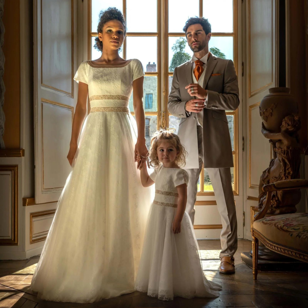 un couple avec leur petite fille en robe de mariée