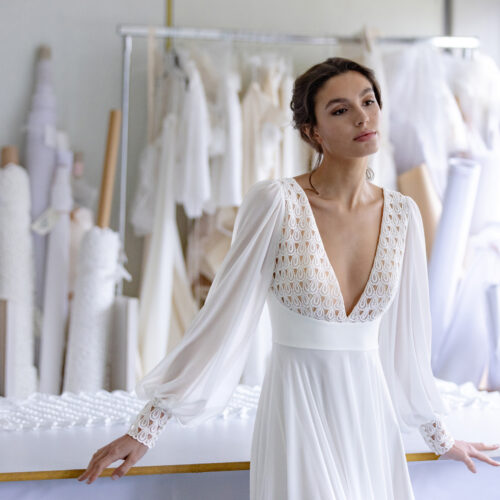 femme dans une robe de mariée bohème et épurée dans un atelier de couture