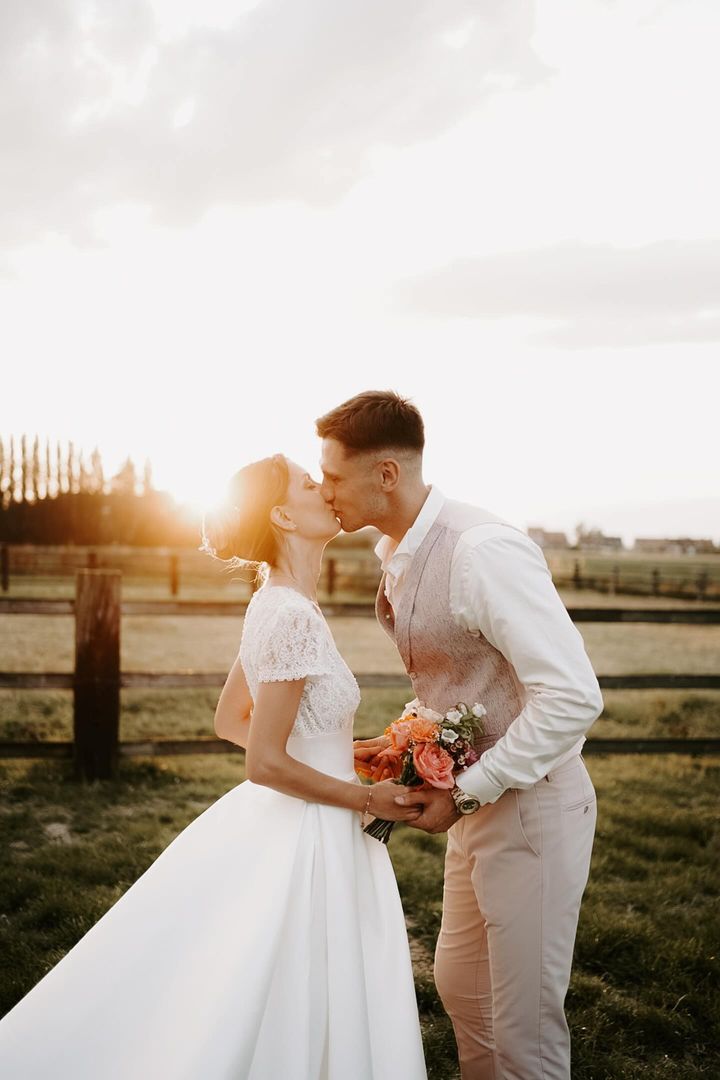 couple de mariés dans un parc avec un coucher de soleil