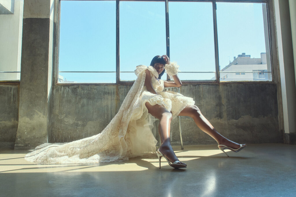 femme assise portant une robe de mariée originale, courte devant avec une longue traîne à l'arrière