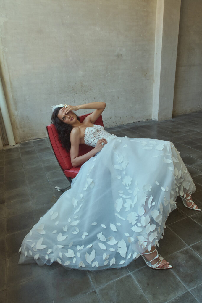 femme sur un fauteuil, habillée d'une robe de mariée glamour en matière façonnée