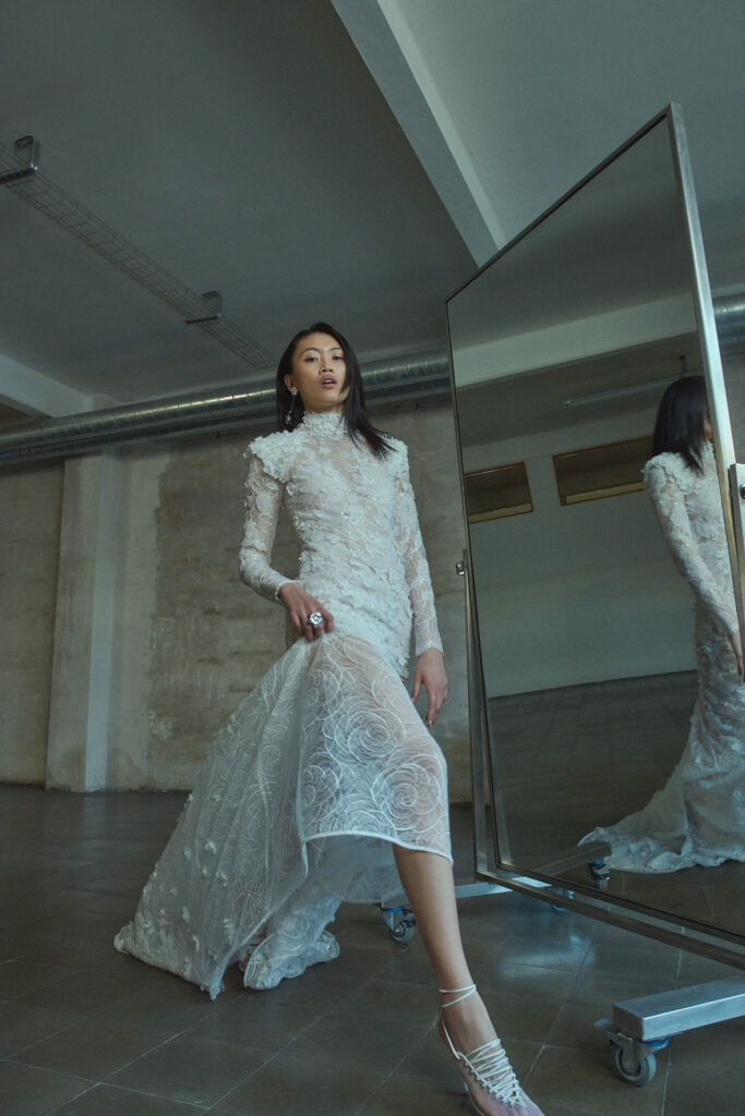 femme habillée d'une robe de mariée sirène glamour, avec une traîne et des manches longues