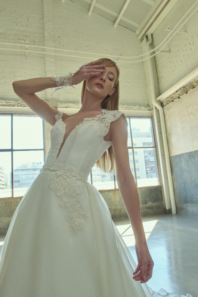 femme habillée d'une robe de mariée princesse glamour et élégante, à détails asymétriques sur les bretelles
