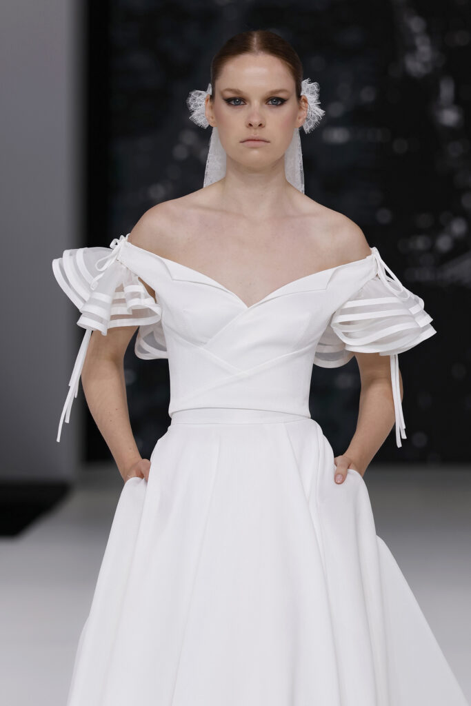 femme dans une robe de mariée à col sur un podium de défilé