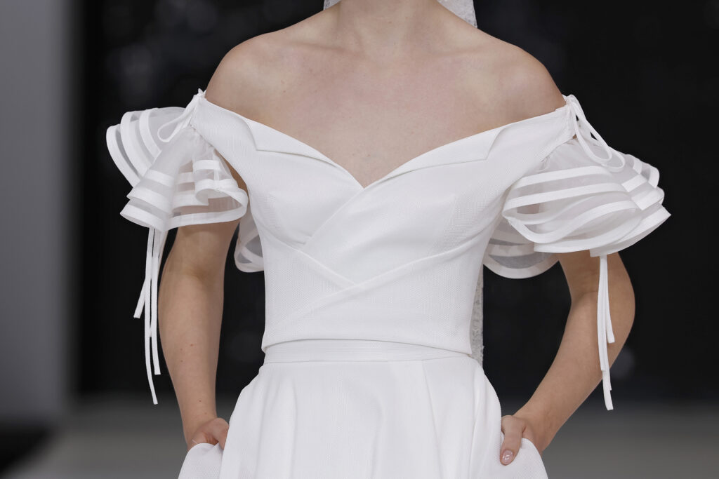 femme dans une robe de mariée à col sur un podium de défilé