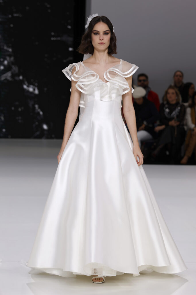 femme dans une robe de mariée à col sur un podium de défilé