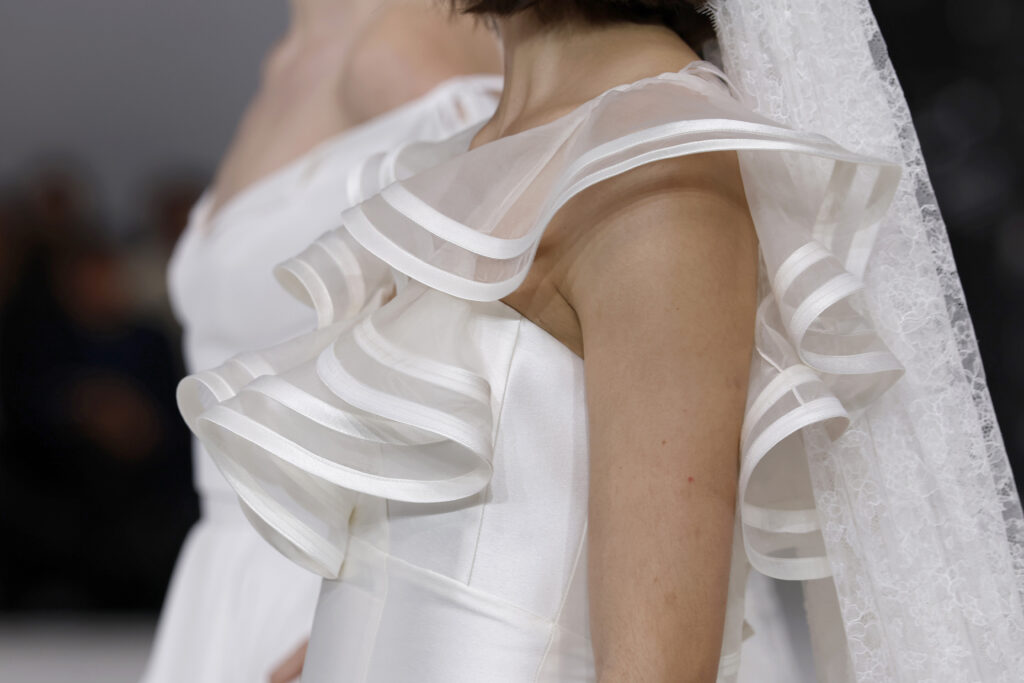 femme dans une robe de mariée à col sur un podium de défilé