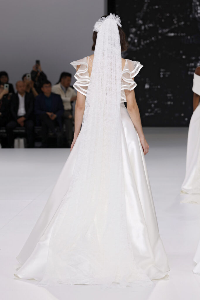 femme dans une robe de mariée à col sur un podium de défilé