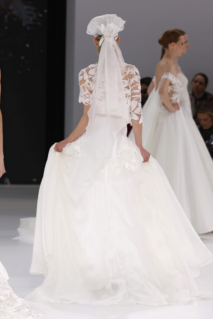 femme dans une robe de mariée avec un top en dentelle et une jupe sur un podium de défilé