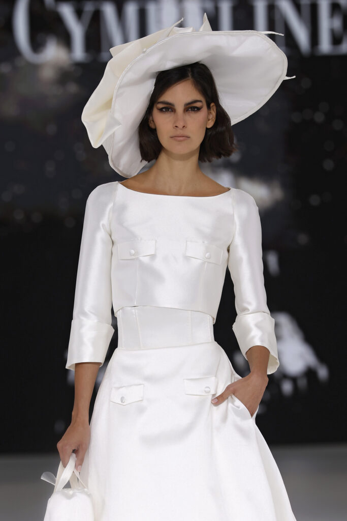 femme dans une robe de mariée avec un top et une jupe sur un podium de défilé
