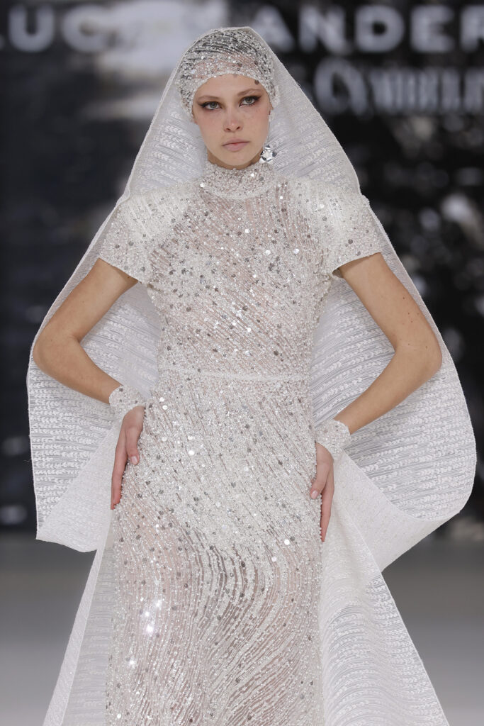 femme dans une robe de mariée sirène brillante en perles sur un podium de défilé