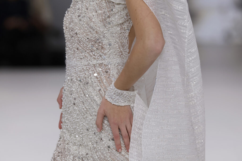 femme dans une robe de mariée sirène brillante en perles sur un podium de défilé