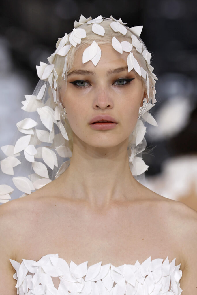femme dans une robe de mariée princesse originale avec un long voile sur un podium de défilé