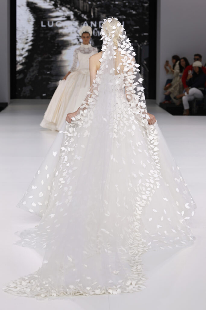femme dans une robe de mariée princesse originale avec un long voile sur un podium de défilé