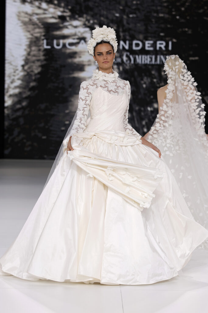 femme dans une robe de mariée princesse à manches longues en dentelle et en taffetas de soie sur un podium de défilé
