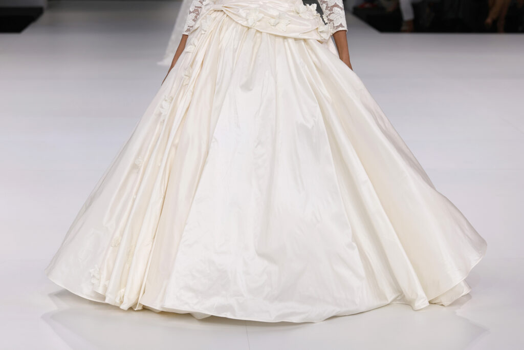 femme dans une robe de mariée princesse à manches longues en dentelle et en taffetas de soie sur un podium de défilé