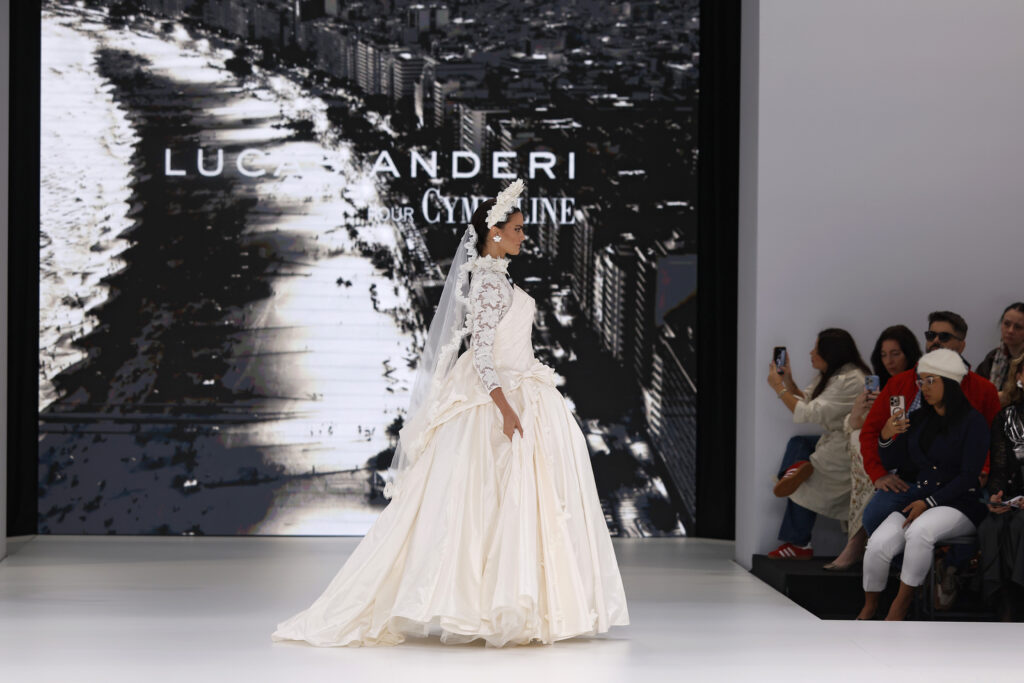 femme dans une robe de mariée princesse à manches longues en dentelle et en taffetas de soie sur un podium de défilé