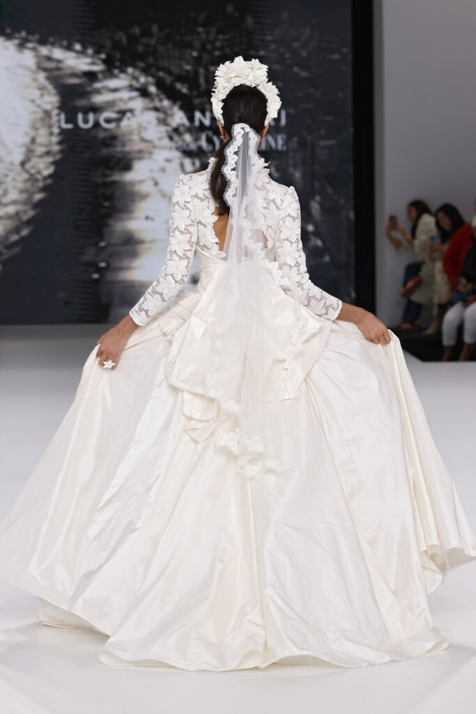 femme dans une robe de mariée princesse à manches longues en dentelle et en taffetas de soie sur un podium de défilé