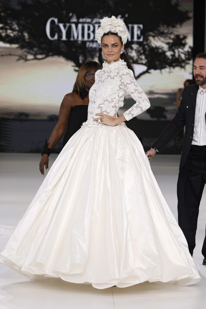 femme dans une robe de mariée princesse à manches longues en dentelle et en taffetas de soie sur un podium de défilé