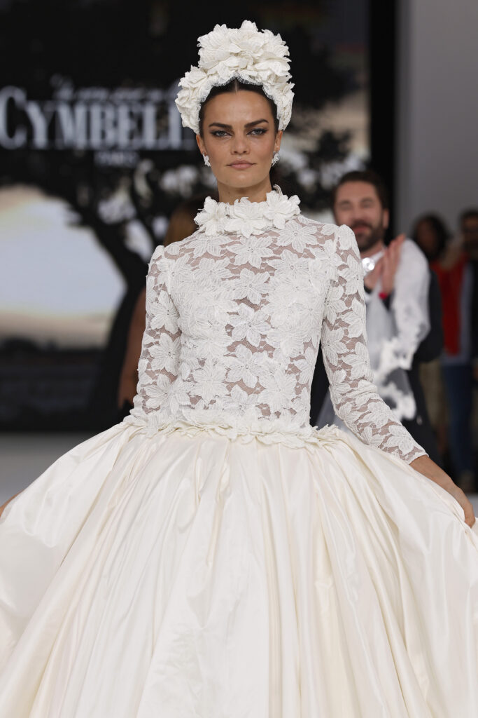 femme dans une robe de mariée princesse à manches longues en dentelle et en taffetas de soie sur un podium de défilé
