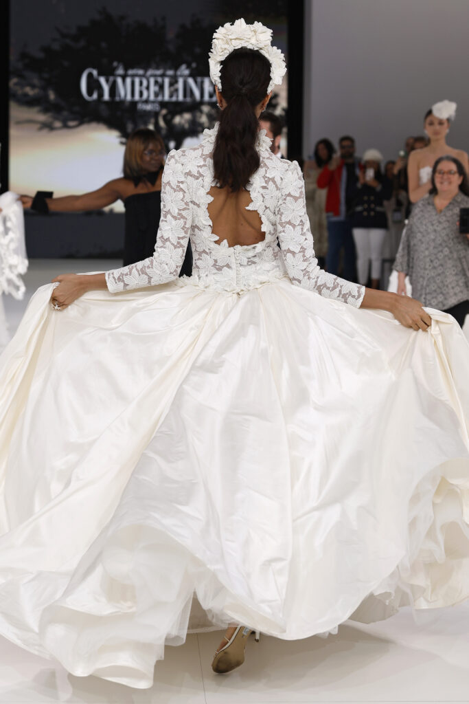 femme dans une robe de mariée princesse à manches longues en dentelle et en taffetas de soie sur un podium de défilé