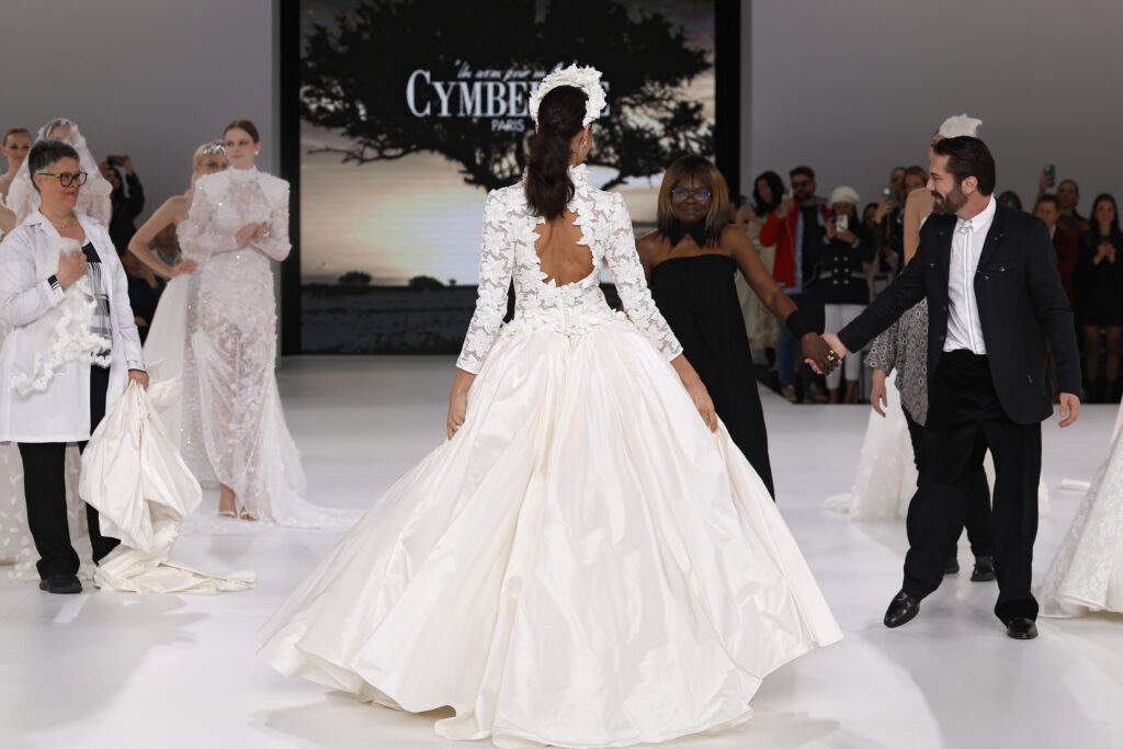 femme dans une robe de mariée princesse à manches longues en dentelle et en taffetas de soie sur un podium de défilé