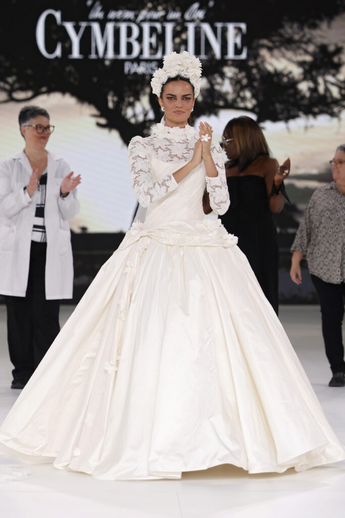 femme dans une robe de mariée princesse à manches longues en dentelle et en taffetas de soie sur un podium de défilé