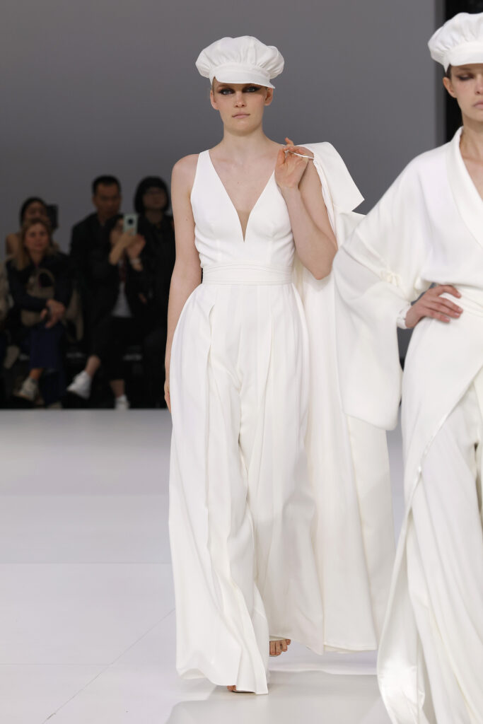 femme dans une combinaison de mariage sur un podium à un défilé