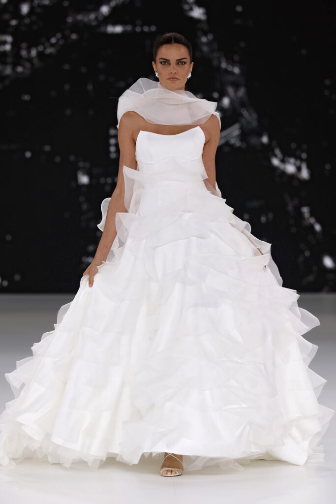 femme dans une robe de mariée à volants sur un podium de défilé