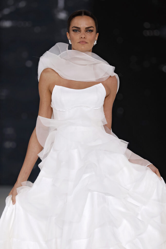 femme dans une robe de mariée à volants sur un podium de défilé