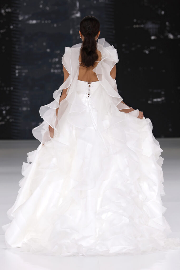femme dans une robe de mariée à volants sur un podium de défilé