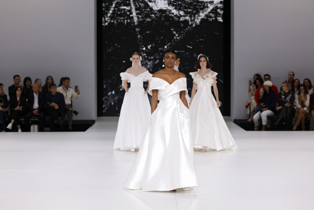 femme dans une robe de mariée à col sur un podium de défilé