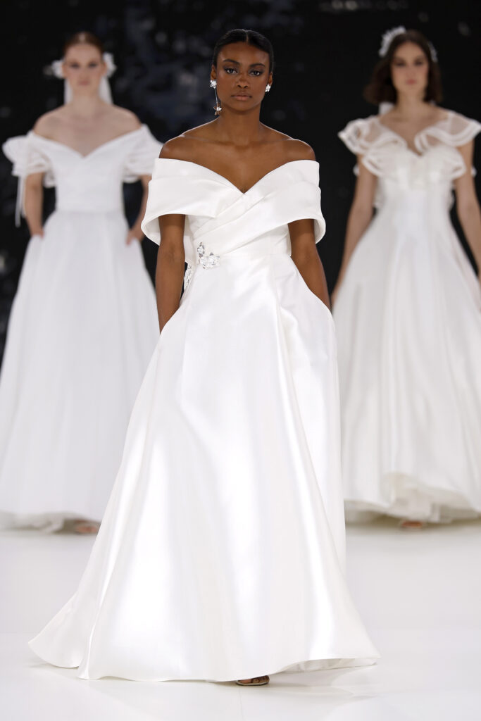 femme dans une robe de mariée à col sur un podium de défilé