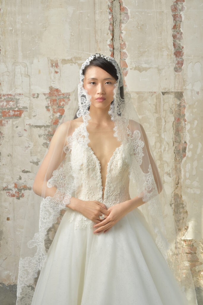 Femme portant une robe de mariée princesse avec un long voile aux finitions en dentelle