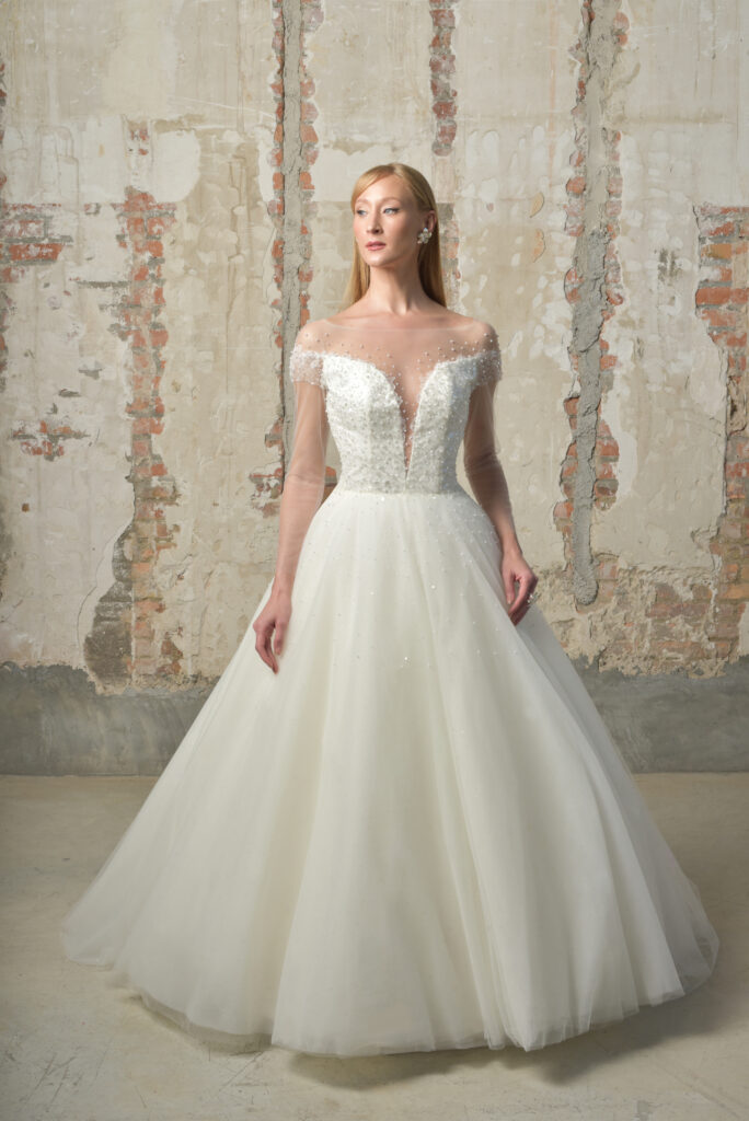 femme dans une robe de mariée princesse brillante à perles et à manches longues effet illusion
