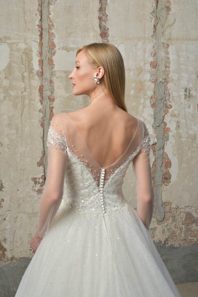 femme dans une robe de mariée princesse brillante à perles et à manches longues effet illusion