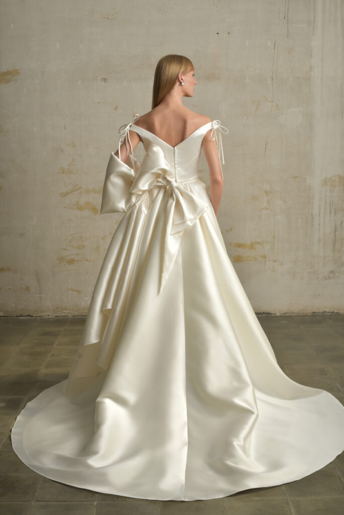 femme dans une robe de mariée princesse en mikado avec un grand nœud et un sac à main