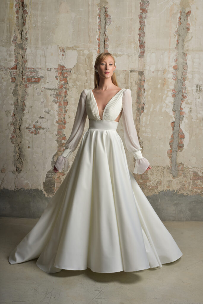 femme dans une robe de mariée épurée et fluide avec des manches longues amovibles