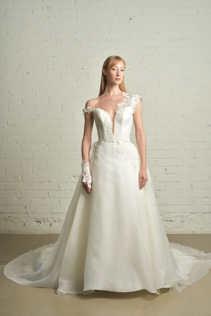 femme habillée d'une robe de mariée princesse glamour et élégante, à détails asymétriques sur les bretelles