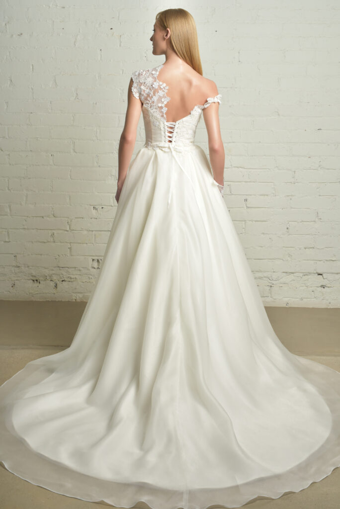 femme habillée d'une robe de mariée princesse glamour et élégante, à détails asymétriques sur les bretelles
