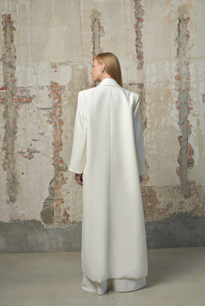 femme dans une tenue de cérémonie avec un manteau long et un pantalon blanc