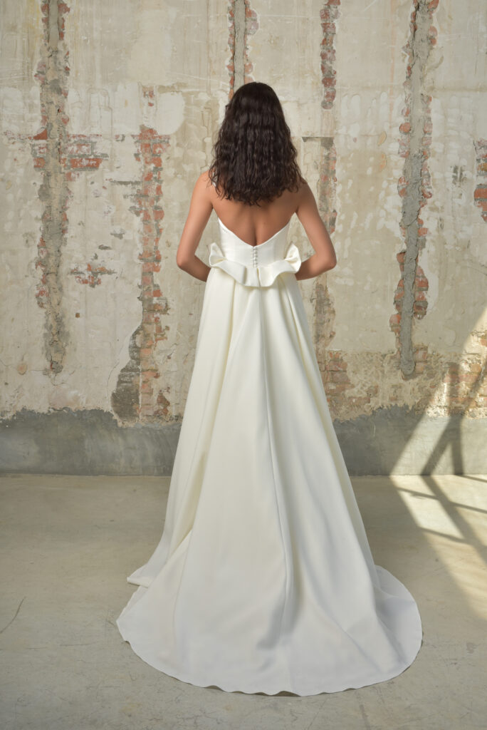 femme dans une robe de mariée sirène glamour avec une surjupe à traîne dans un studio