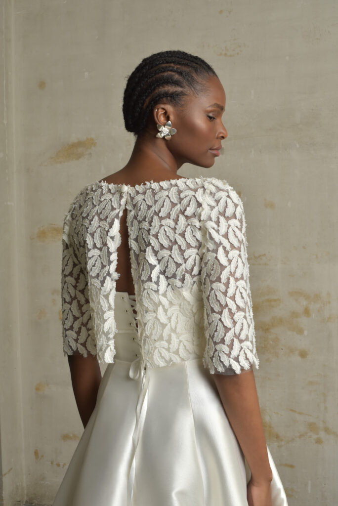 femme dans une tenue de cérémonie avec un top en dentelle rebrodée plume