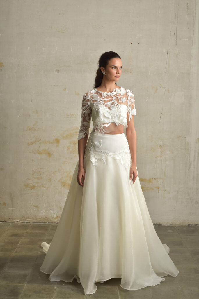 femme habillée d'une tenue de mariée composée d'une jules longue et volumineuse, d'un top bandeau et d'un top court en raphia