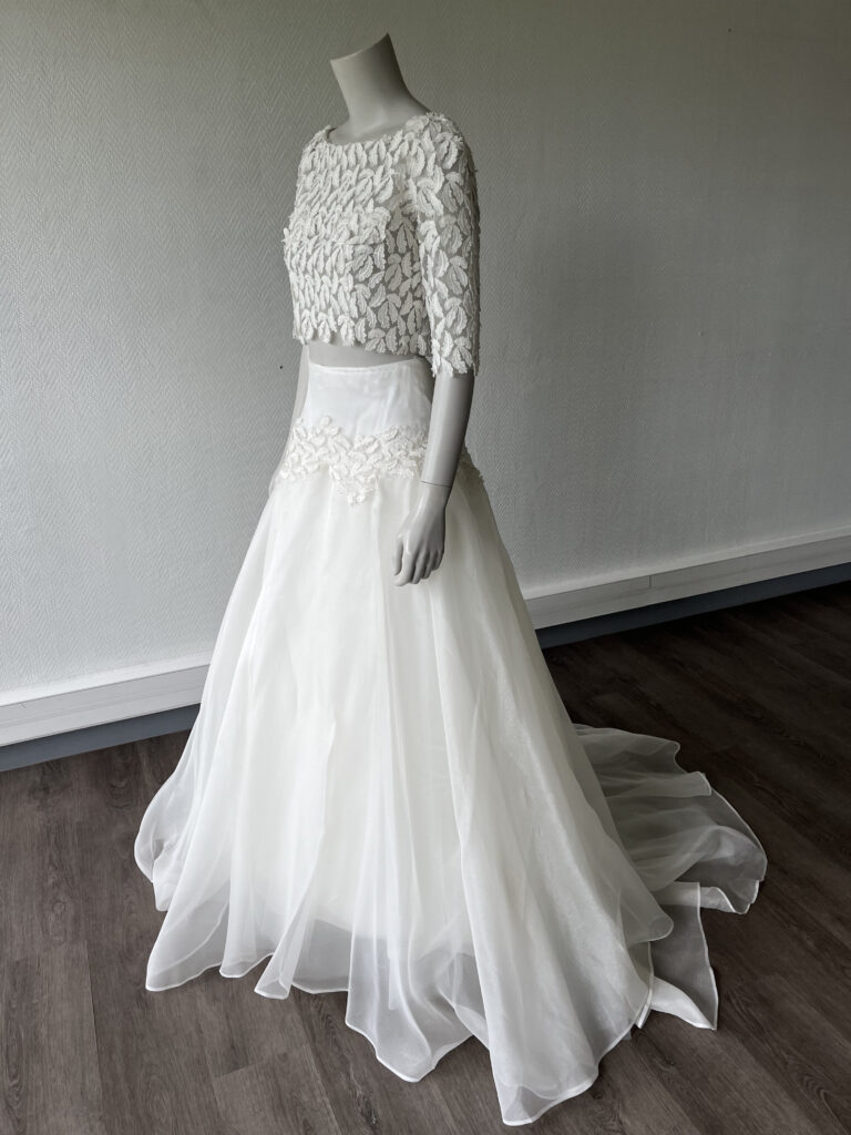 femme dans une tenue de cérémonie avec un top et une jupe bohème en dentelle rebrodée plume